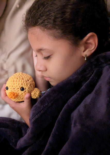 A young girl sleeping with her yellow amigurumi chick plushie